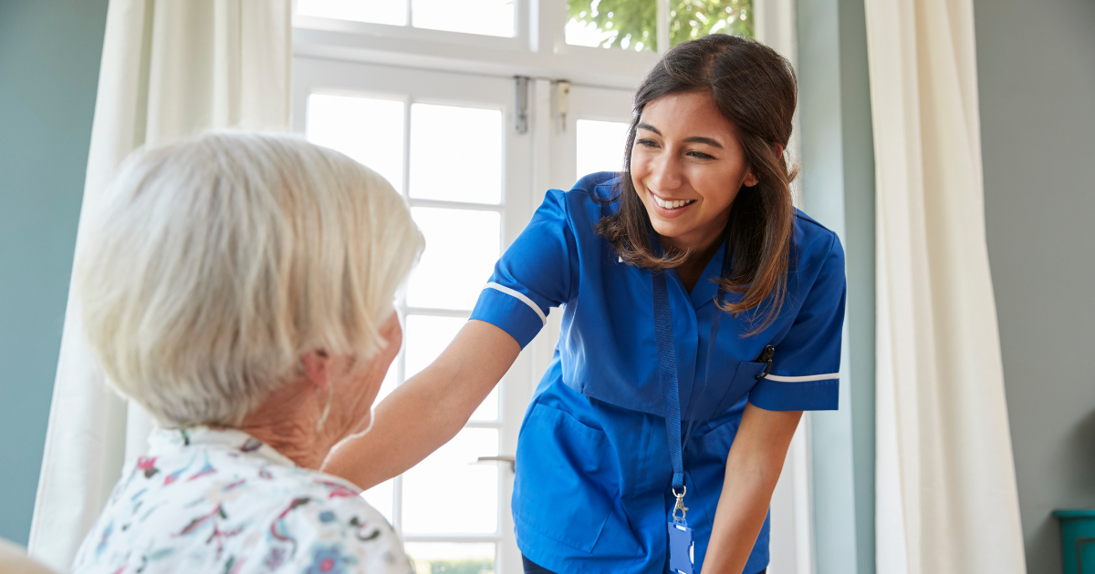 A woman enjoys her home health care job as she cares for a senior patient.