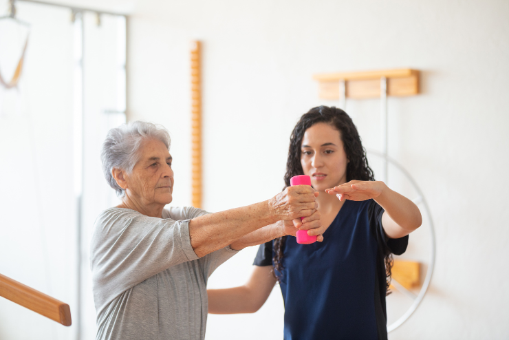 A physical therapist helps an older client with exercise, representing how physical therapy in Killeen can help.