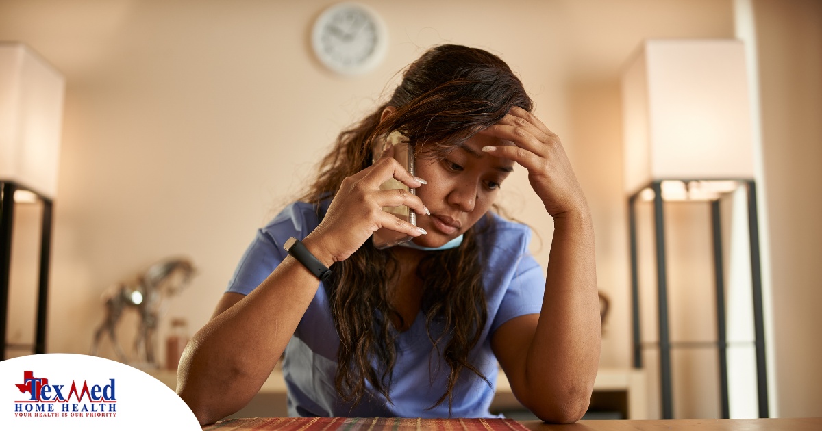 A nurse makes a call while looking extremely exhausted representing the bad effects of nurse burnout.