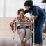 A care professional helps an older woman get up with the use of a walker, representing how occupational therapy can help with recovery.
