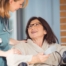 A care provider helps a patient in a wheelchair representing the benefits of medical care at home.