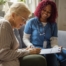 A healthcare professional helps an older patient fill out a form, representing what happens when the requirements for home health care eligibility are met.