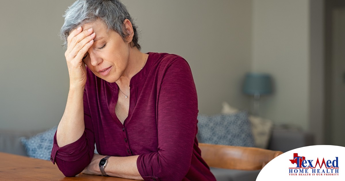 A woman holds her head in her hand, representing the stress that new family caregivers go through.