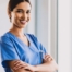 A woman in scrubs smiles representing the satisfaction of finding out how to become a home health aide.