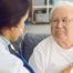 A doctor examines an older man with a stethoscope, representing pneumonia in elderly adults.