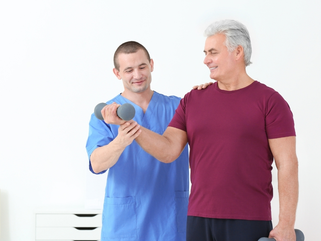 Physical Therapy in Waco (2) Caregiver assisting an older man with dumbbell exercises during Physical Therapy in Waco